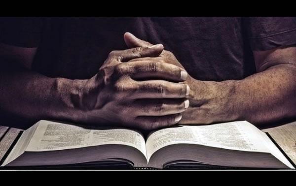 man with hands on bible