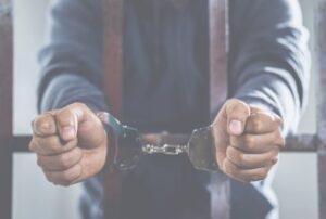 man in handcuffs behind bars